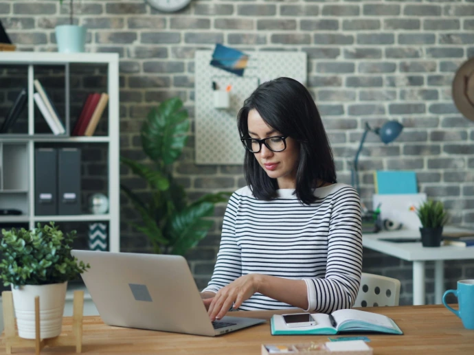 a woman sitting at a table using a laptop computer
