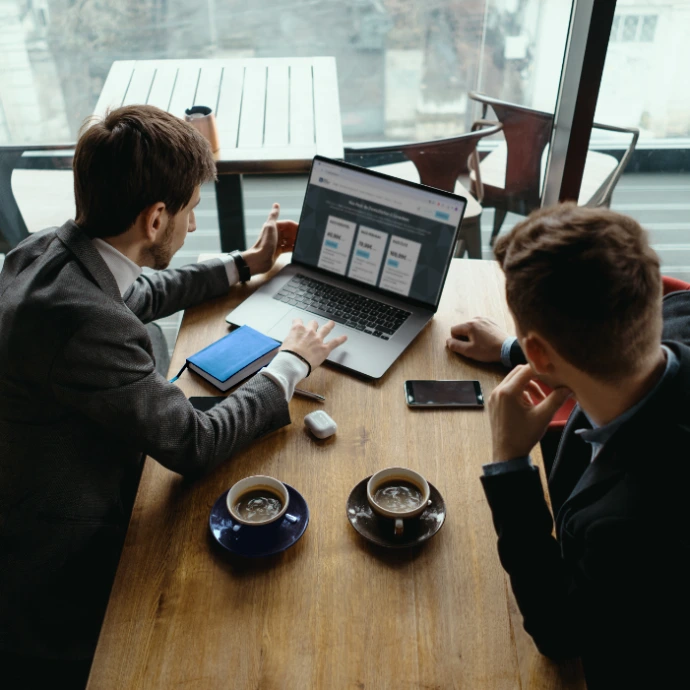 Deux entrepreneurs en réunion professionnelle analysant des solutions de création d’entreprise en Belgique sur ordinateur, illustrant une consultation stratégique autour de la domiciliation d’entreprise en Flandre, le choix du siège social et l’accompagnement administratif pour lancer une activité à Zaventem.